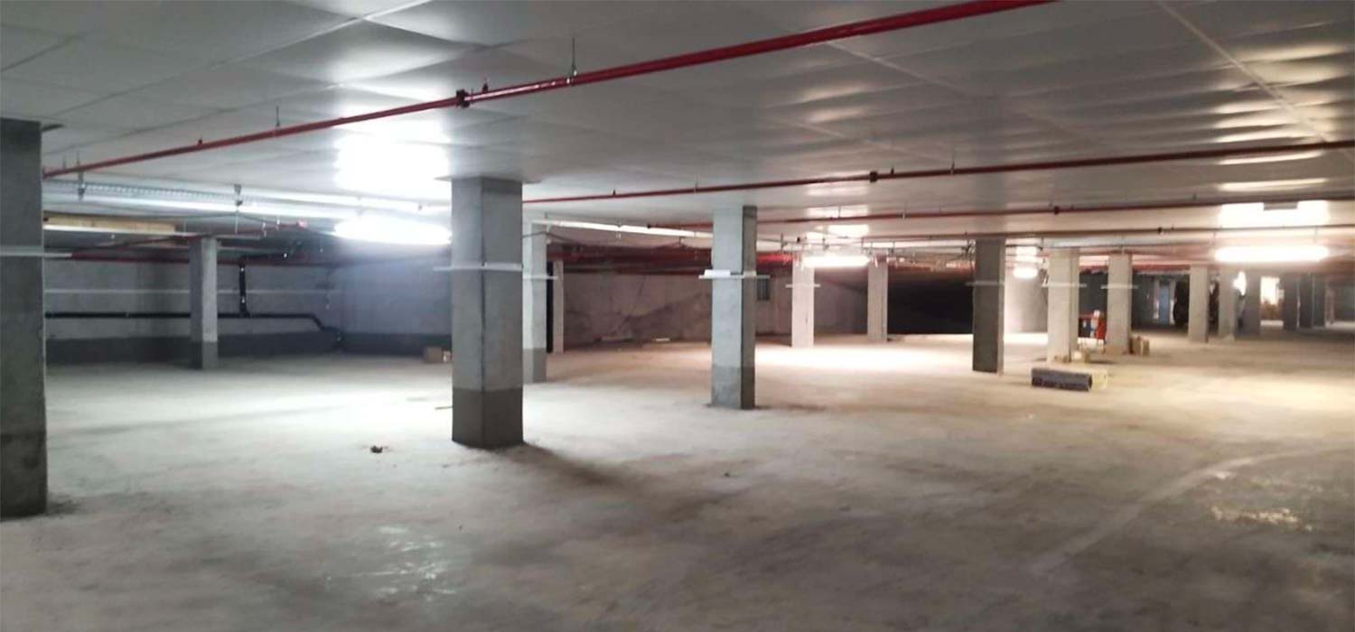 weitläufige Tiefgarage mit Wärmeschutz an der Decke und einem roten Leitungssystem
